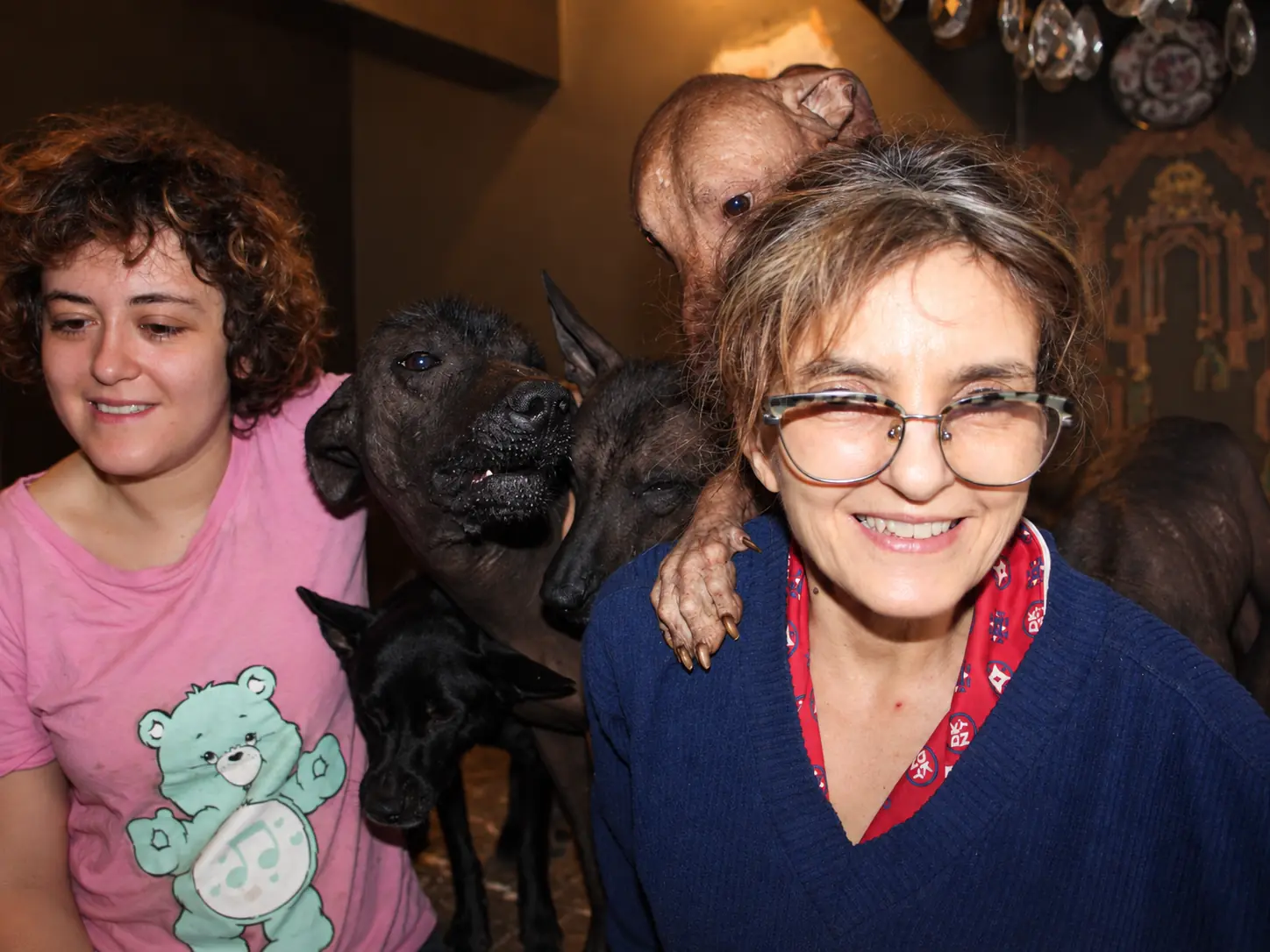 Marcela smiles while a Xoloitzcuintli rests a paw on her shoulder