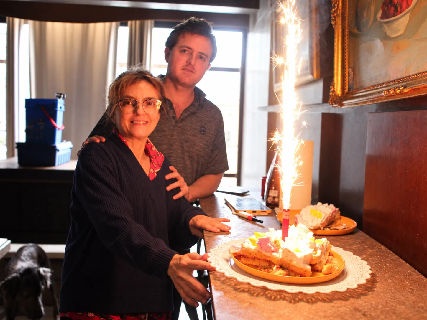 Marcela and Fernando beside the birthday cake and a lit sparkler